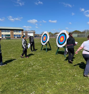 a group of people walking up to an archery target