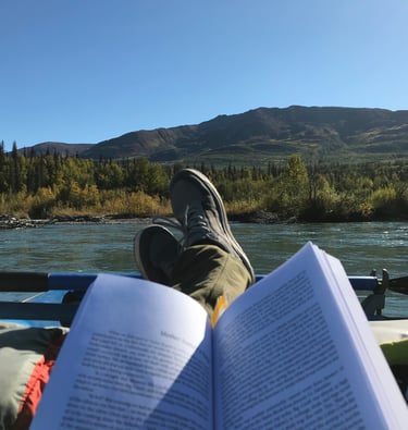 Business owner reading a book on a river