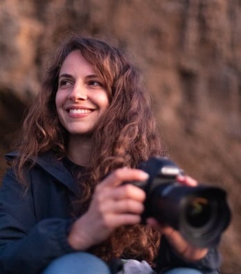 a woman sitting on a rock with a camera