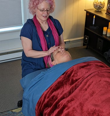 Renee with relaxed client on massage table receiving Reiki Odyssey and Chakra Balancing..