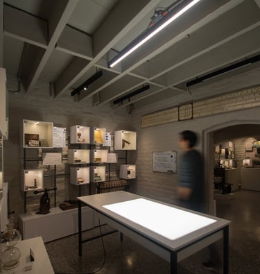 Sala de exposiciones de museo, vitrinas de caja y mesa iluminada al centro