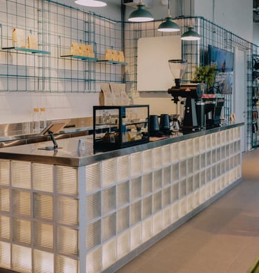 Una cafeteria con barra y mostrador, iluminacion integrada