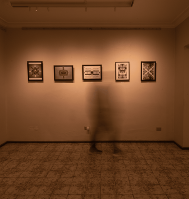 Una persona parada en una habitación con cuadros en la pared. Iluminacion calida