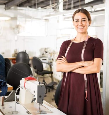 Una costurera sonriente con una cinta métrica de pie.
