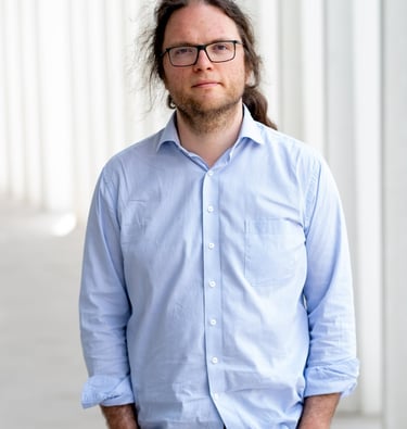 a man with long hair and glasses on a sidewalk