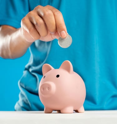 A child's hand putting a coin into a ceramic piggy bank