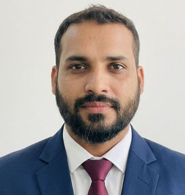 Professional headshot of a bearded man wearing a blue suit and maroon tie for a corporate profile.