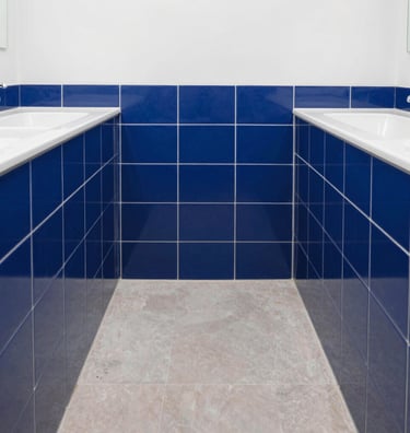 Straight-on architectural photograph of a perfectly aligned modern bathroom dado under bright natural daylight, crisp royal blue tile joints, professional masonry work