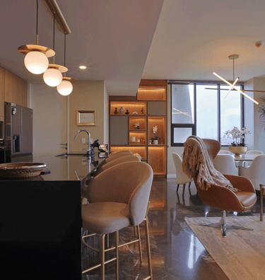 Sala comedor moderno con acabados en mármol, iluminación cálida y mobiliario contemporáneo | KARÄNA