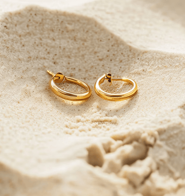 a pair of gold hoop earrings with a gold hoop earrings