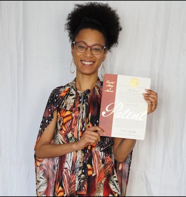 Photography of Ryan wearing a dress, smiling and holding her issued U.S. Patent document.