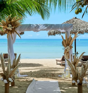 a beach wedding ceremony with a white aisle lined with chairs and umbrellas