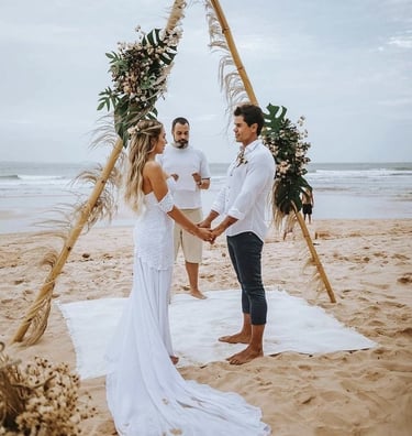a bride and groom standing on the beach