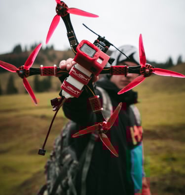 a man holding a red and white remote controlled fpv drone with a gopro on top and Iflight straps hol