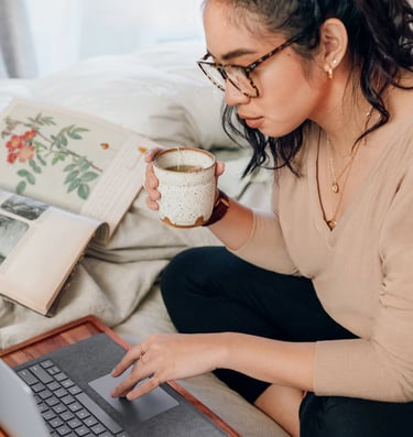 Woman drinking tea in front of computer