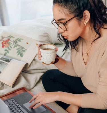 Woman drinking tea in front of computer