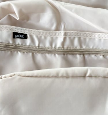 Cream colored packing cubes laid out for organizing clothing during travel