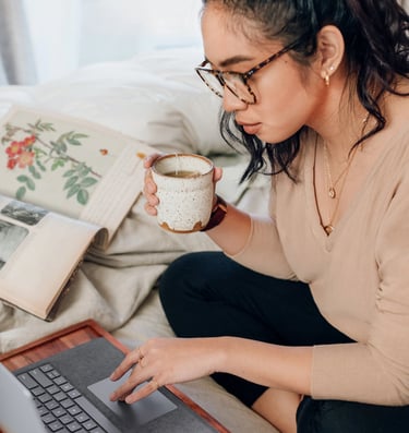 Woman drinking tea in front of computer