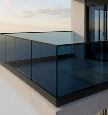 Modern high-rise apartment balcony featuring a sleek black-framed glass railing system at sunset.