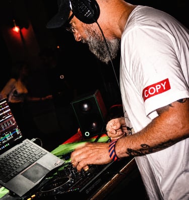 Dacarter DJ wearing headphones mixing music on a controller with a laptop at a club event.