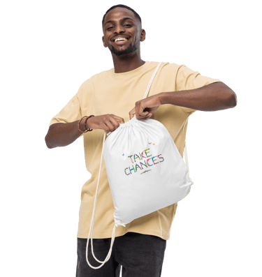 A man holding a tote bag with the words Take Chances printed on in tropical exotic wordart