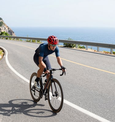 Road cyclist speeding along a coastal route with sea and hills in the background. avvicina il ciclis