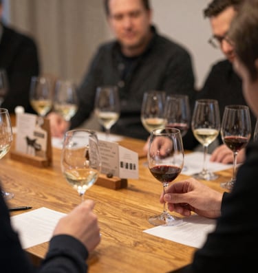 Elegant wine glasses filled with red wine against a minimalist black and burgundy backdrop.