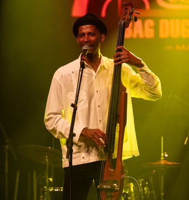 a man in a white shirt and hat playing bass