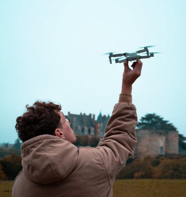 Photographie de Hugo Goujon-Delettre technicien pilotant un drone devant un château.