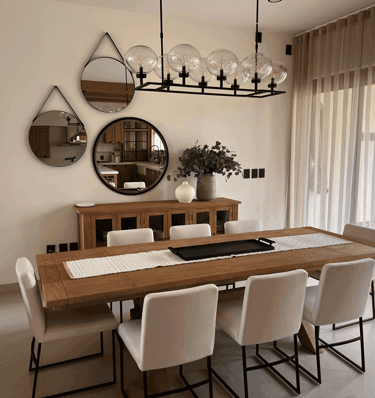 Comedor con mesa de madera, sillas blancas, cortinas y conjunto decorativo de espejos | KARÄNA