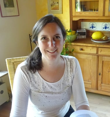 a friendly smiling woman sitting at a table with a book