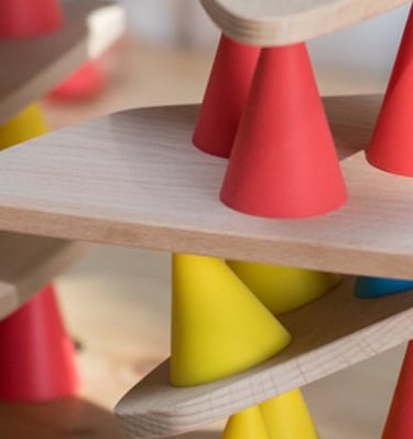 Children creating a structure from colorful silicone cones and wooden tables in the room