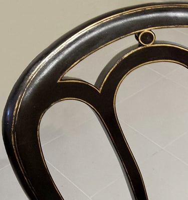 Détail d'une chaise bistrot en bois dont la peinture a été restaurée avec ses filets dorés.