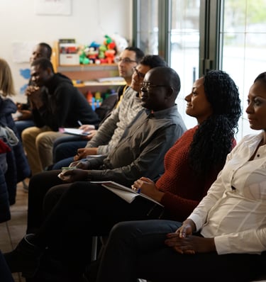 Diverse group of adult students attending a community workshop and taking notes in a classroom.
