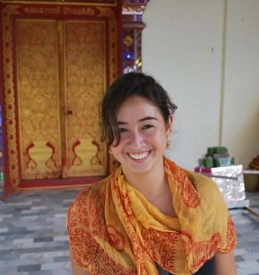 Clara Coelho em frente a templo na Índia, anos após sua primeira formação. Sorriso genuíno e vivênci