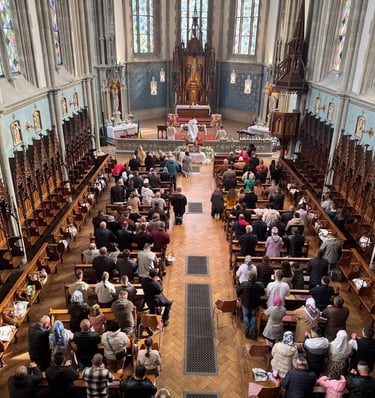 Congregation attending a mass inside a gothic revival church with ornate wood carvings