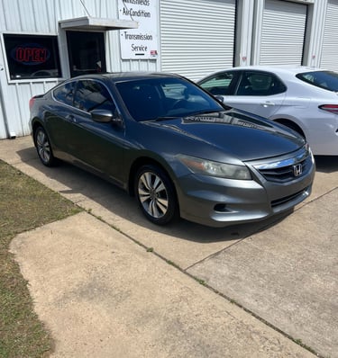 Dark gray Honda Accord coupe parked in front of an auto repair shop for transmission service and oil change.