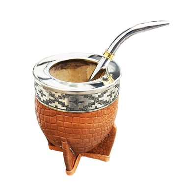 Handcrafted leather yerba mate gourd with silver rim and bombilla straw on a white background.