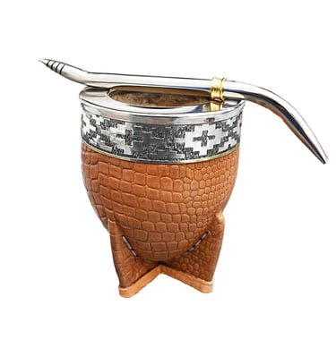Handcrafted leather mate gourd with silver rim and stainless steel bombilla straw on a white background.