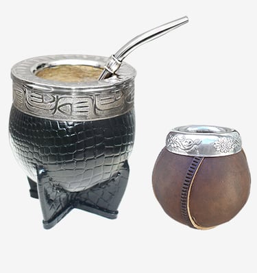 Two traditional yerba mate gourds featuring leather wrapping, ornate silver rims, and a metal bombilla straw.