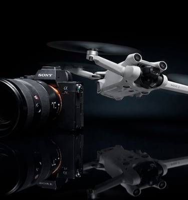 A Sony Alpha mirrorless camera with a G Master lens next to a DJI Mini 3 Pro drone on a dark reflective surface.