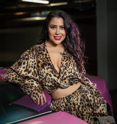 Smiling model in leopard outfit leaning on pink Lamborghini, photographed by Fred Art Studio.