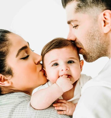 Parents kissing baby during family photoshoot – lifestyle family photography by Fred Art Studio