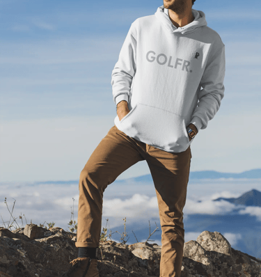 a man standing on a mountain top with a golf ball in his hand