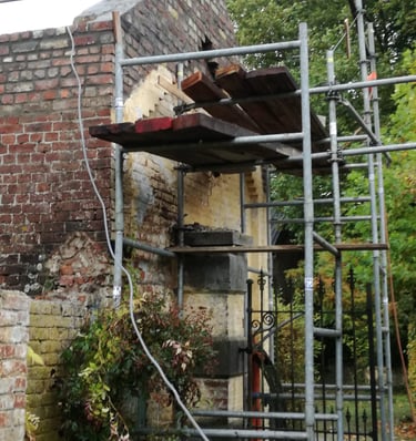 Travaux de restauration sur maçonnerie ancienne avec échafaudage sur façade en briques