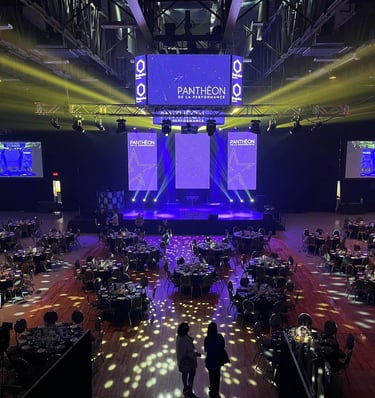 A grand ballroom setup for the Pantheon de la Performance gala with round tables and stage lighting.