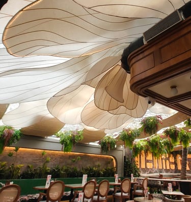 Modern restaurant interior featuring unique floral petal ceiling installations and hanging greenery decor.