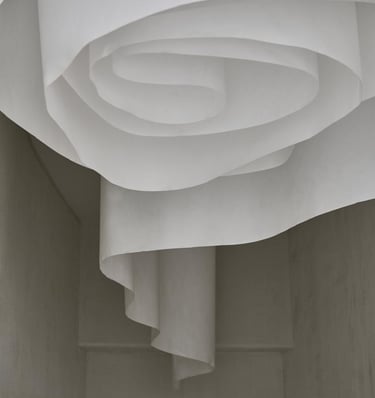 Minimalist white paper art installation with flowing spiral curves in a modern interior.