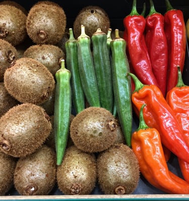A vibrant market scene showing crates of fresh chestnuts and padrón peppers ready for export.