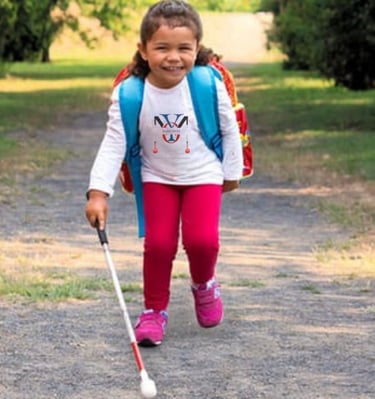 Child with strabismus walking with a O&M white cane for the legally blind and visually impaired with low vision